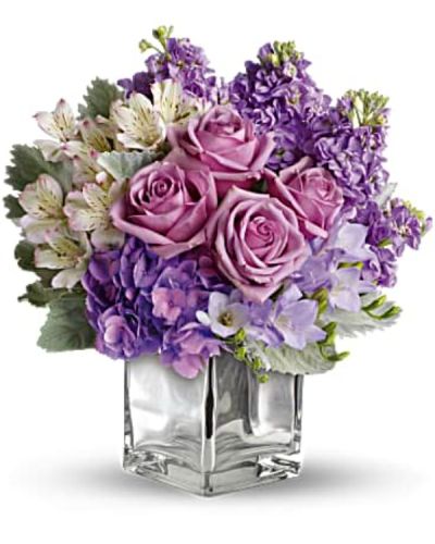 Visions of sugar plum fairies dance to life with this magical bouquet. Lush lavenders, frosty whites and silvery greens look romantic and refreshing inside a cool cube vase.
Robust roses, delicate hydrangea and feminine stock make a cool collection inside an icy, clear glass cube vase.